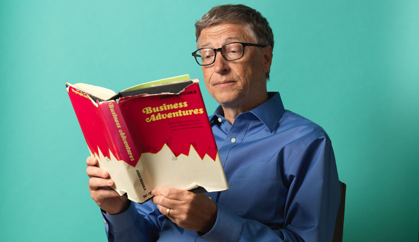 Founder and Chairman of Microsoft Bill Gates holding a copy of Business Adventures by John Brooks.